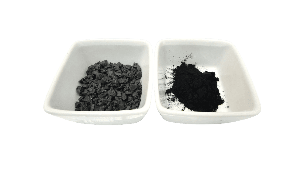 Close-up of black carbon powder and granules in small white dishes, highlighting their texture and appearance for industrial applications and manufacturing processes.